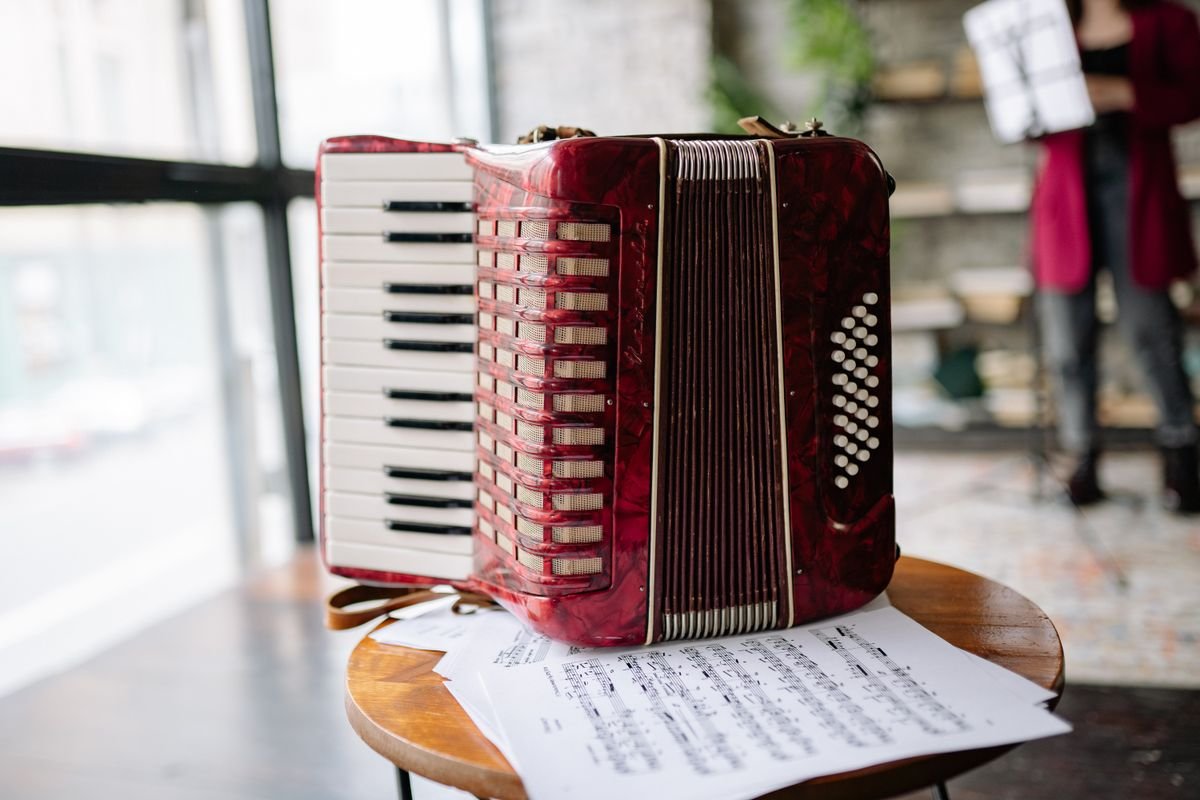 Close-up of a red accordion resting on a table with sheet music