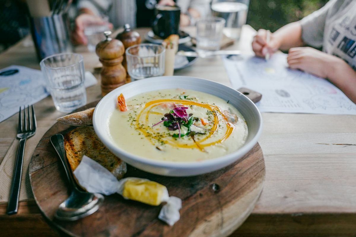 Bowl of soup with rustic bread on a board at a casual cafe table