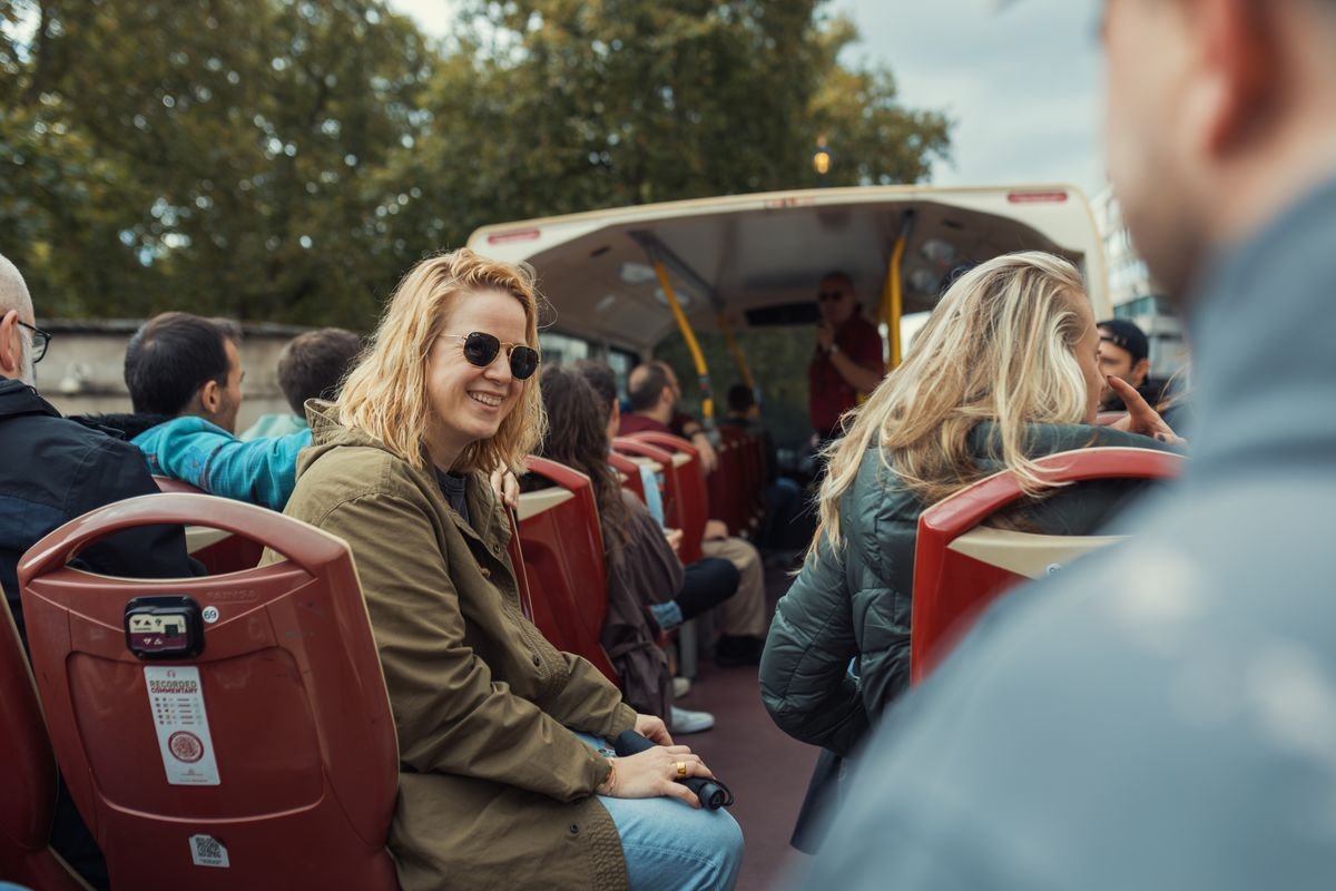 Tourists sitting on an open-top guided tour bus