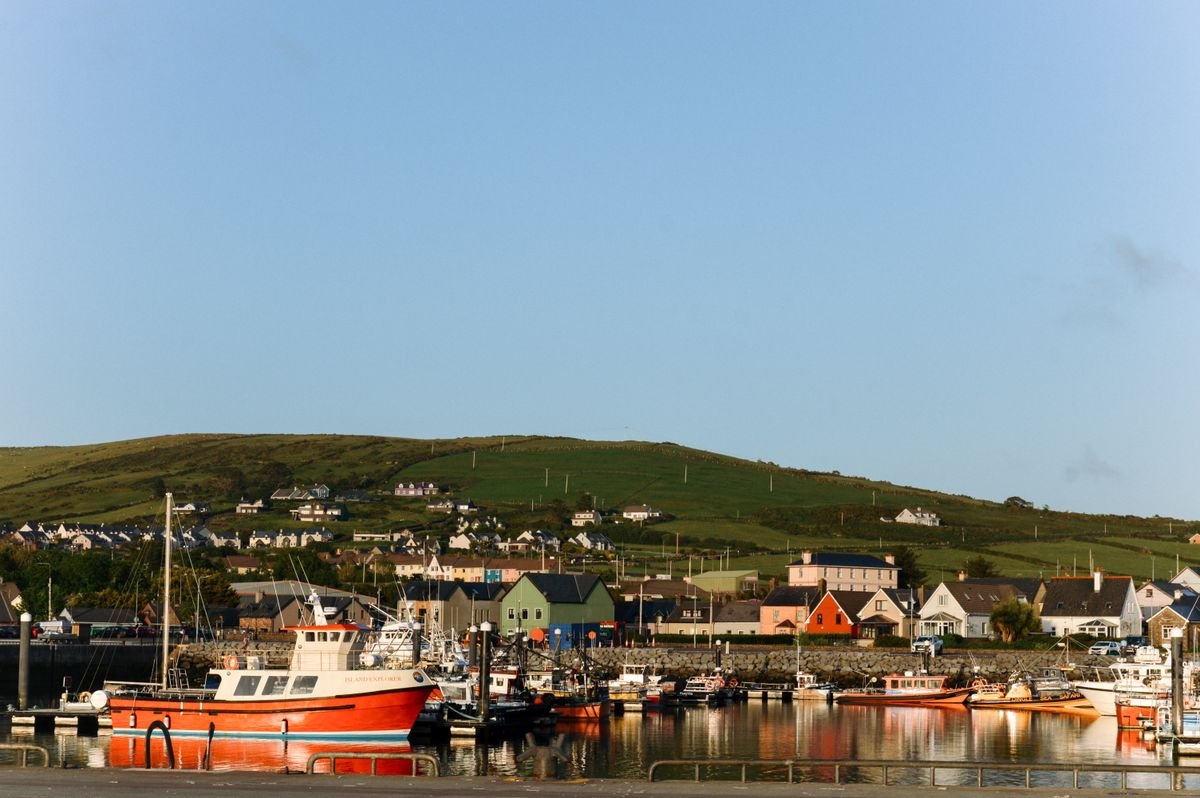 Dingle harbour with fishing boats and the peninsula hills behind