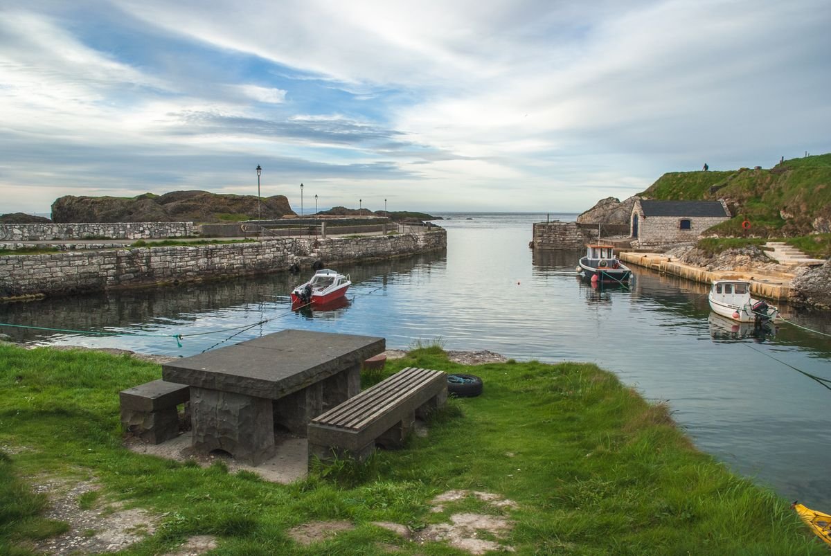Boats in the small stone harbor at Ballintoy