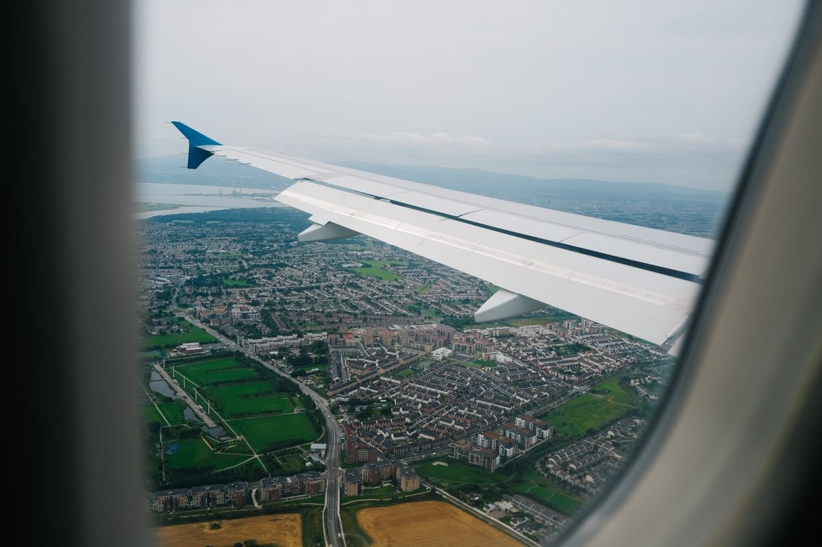 Airplane wing over green landscape on approach