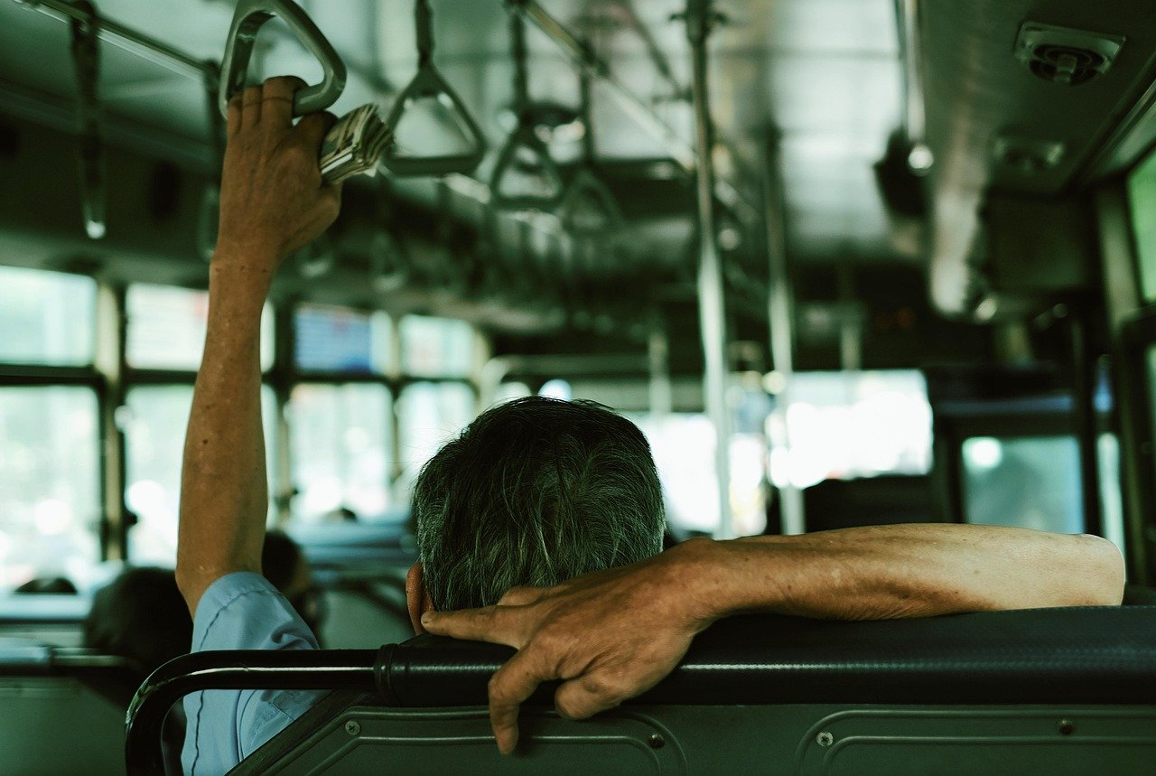 Interior of a public bus with a passenger holding the overhead rail