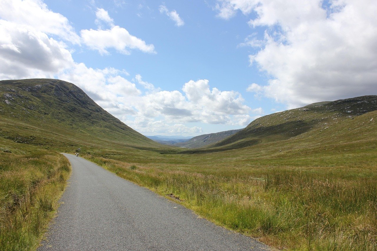 An empty road winding through open Irish mountain moorland