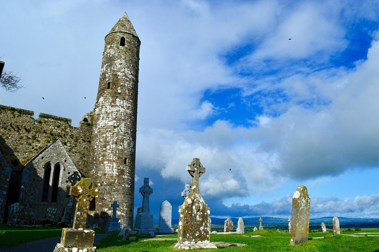 The round tower and Celtic high crosses at the Rock of Cashel under a blue sky