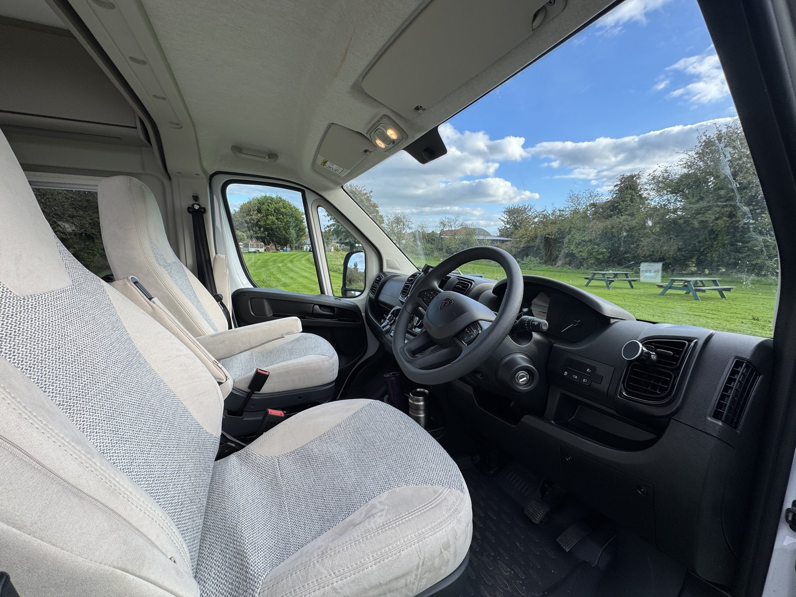 Campervan driver cab interior showing steering wheel and Irish countryside through the windscreen