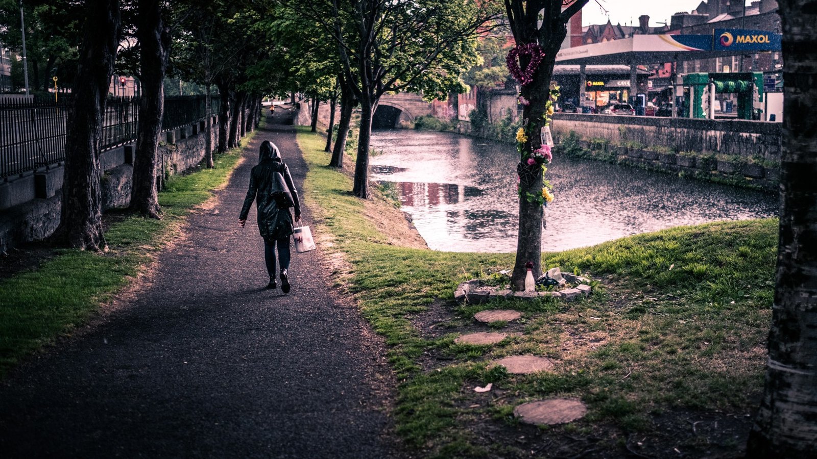 A person walking along a wet canal-side path in Dublin