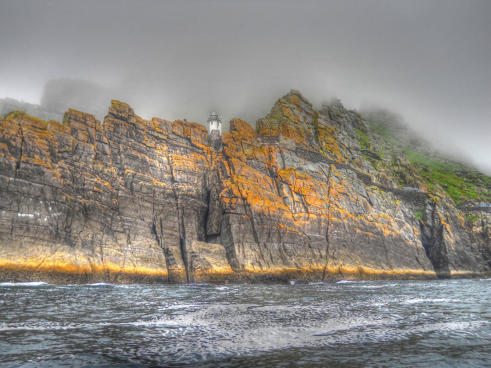 Skellig Michael's cliffs and lighthouse rising out of fog