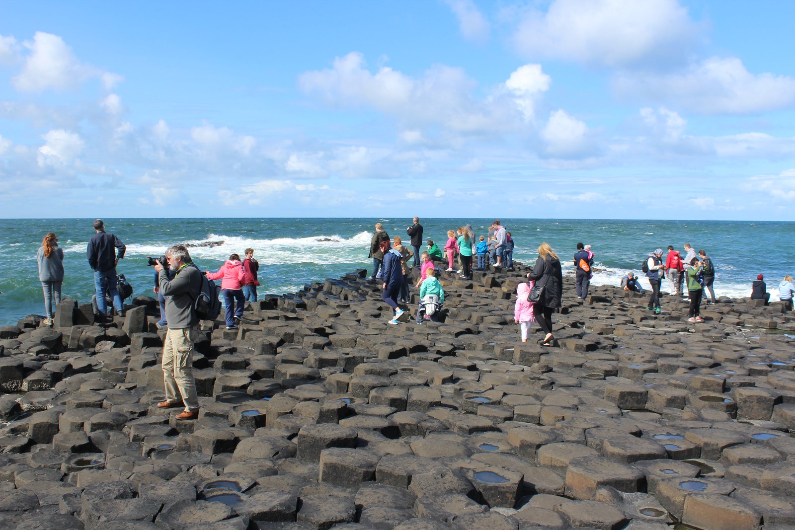 Crowds of visitors standing on the Giant's Causeway stones in the middle of the day