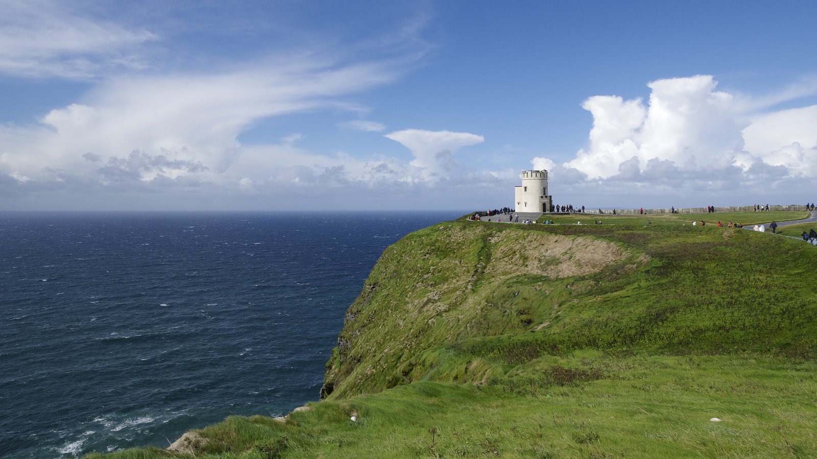 Visitors walking the paved path toward O'Brien's Tower at the Cliffs of Moher