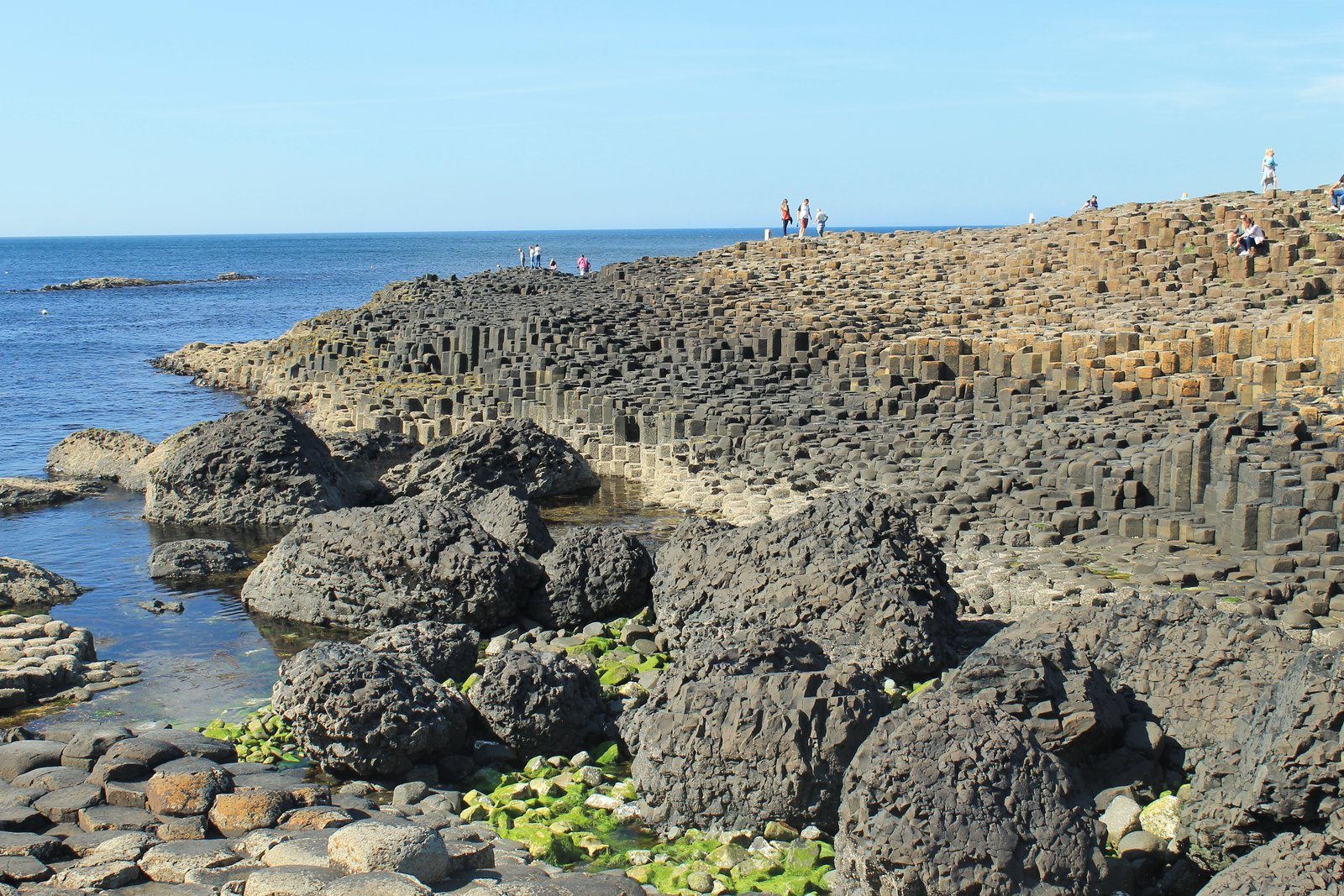 The Giant's Causeway columns running out into the sea on a clear blue day