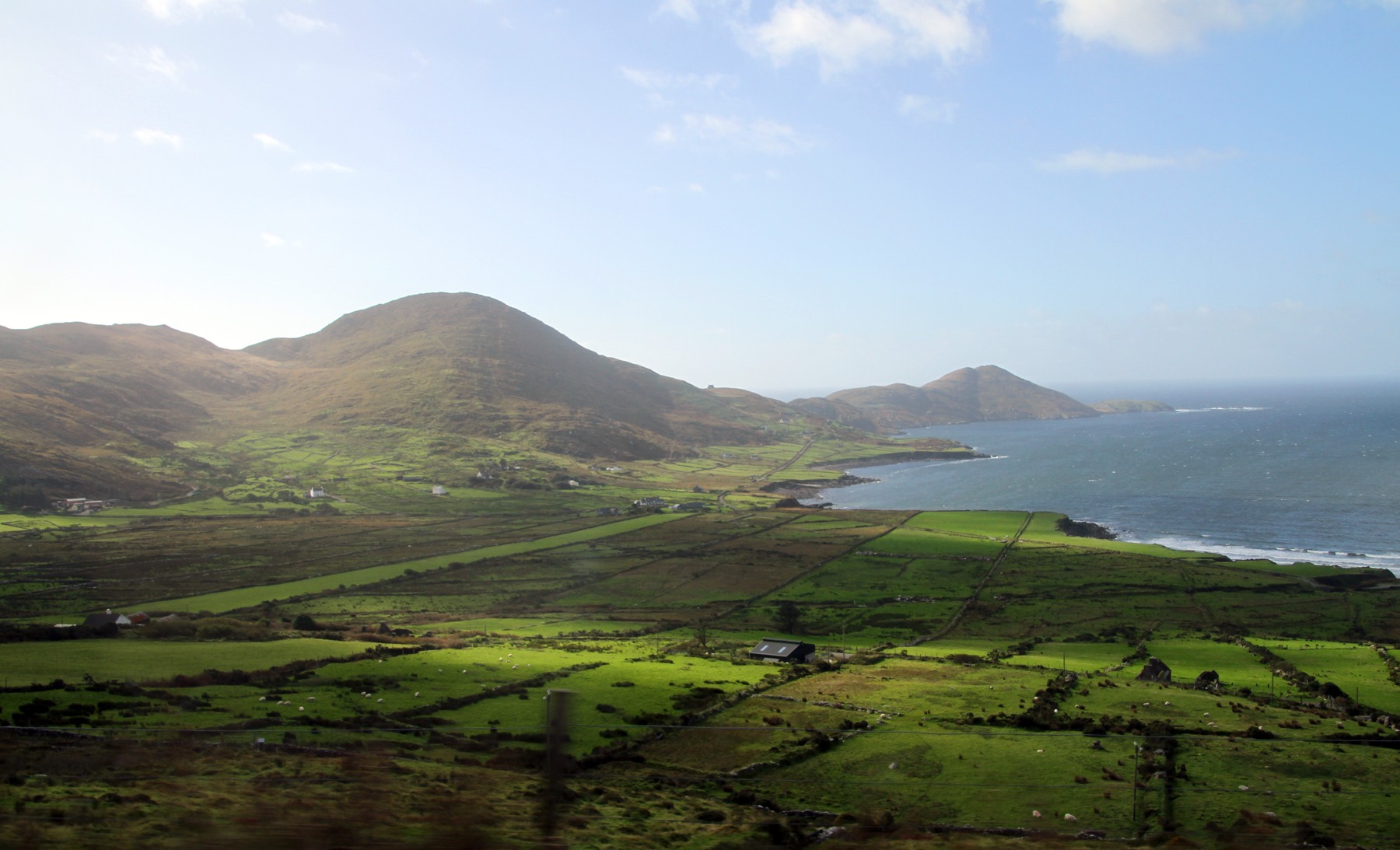 Green fields and mountains beside Ballinskelligs Bay