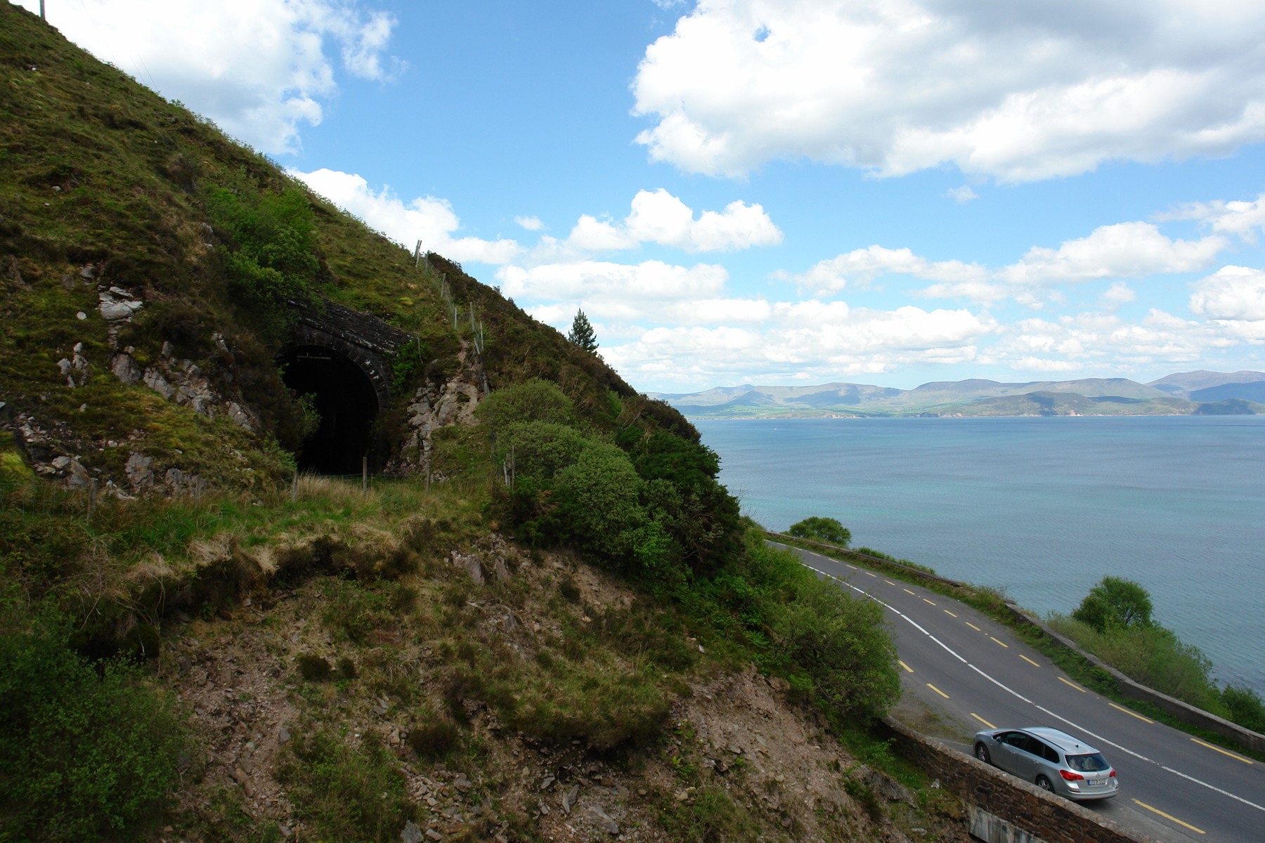 A car on the Kerry coastal road below a disused railway tunnel