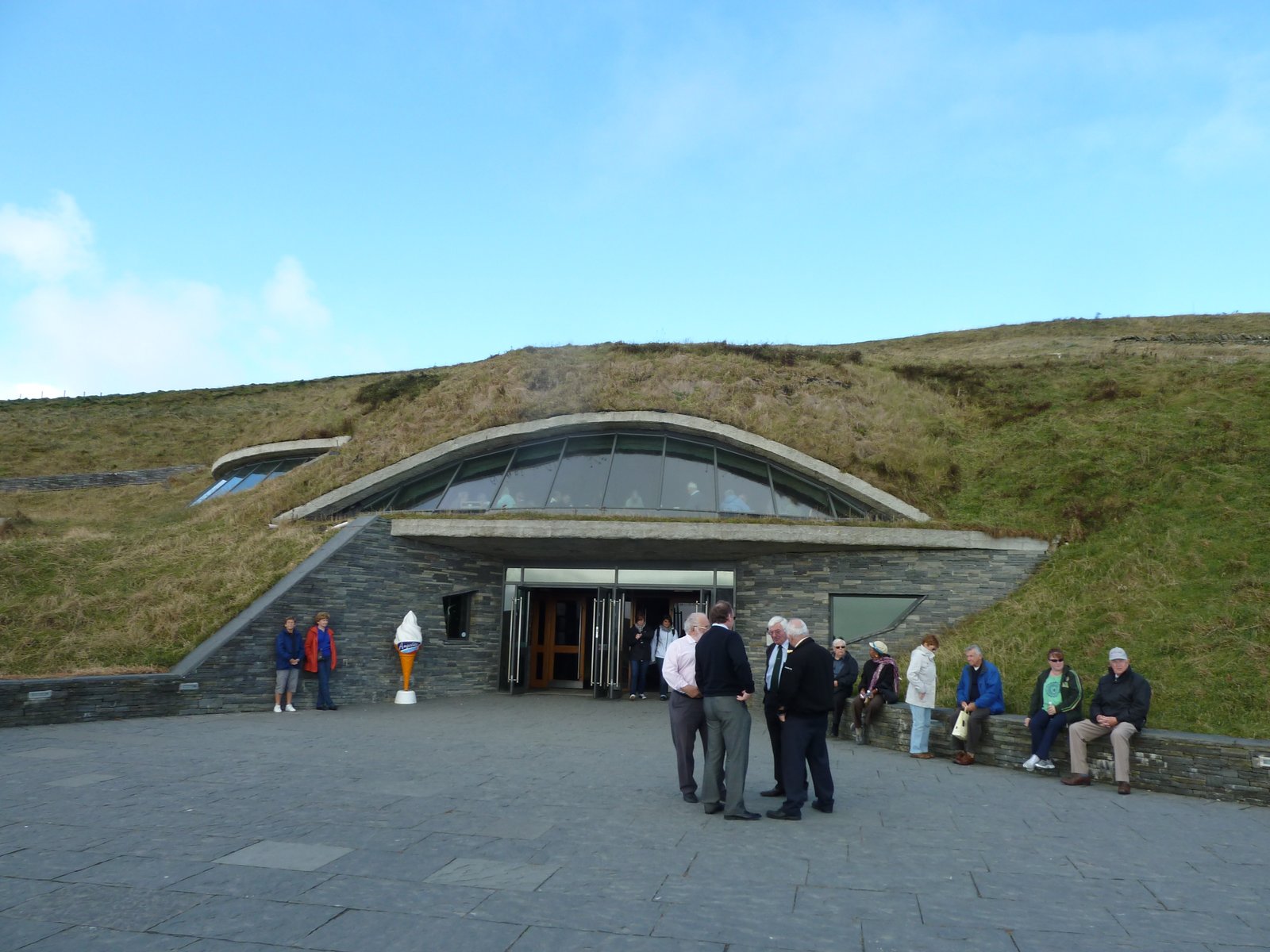 A crowd of tourists outside the grass-roofed visitor centre at the Cliffs of Moher