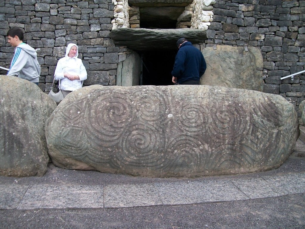 Visitors beside the carved entrance stone and Newgrange doorway